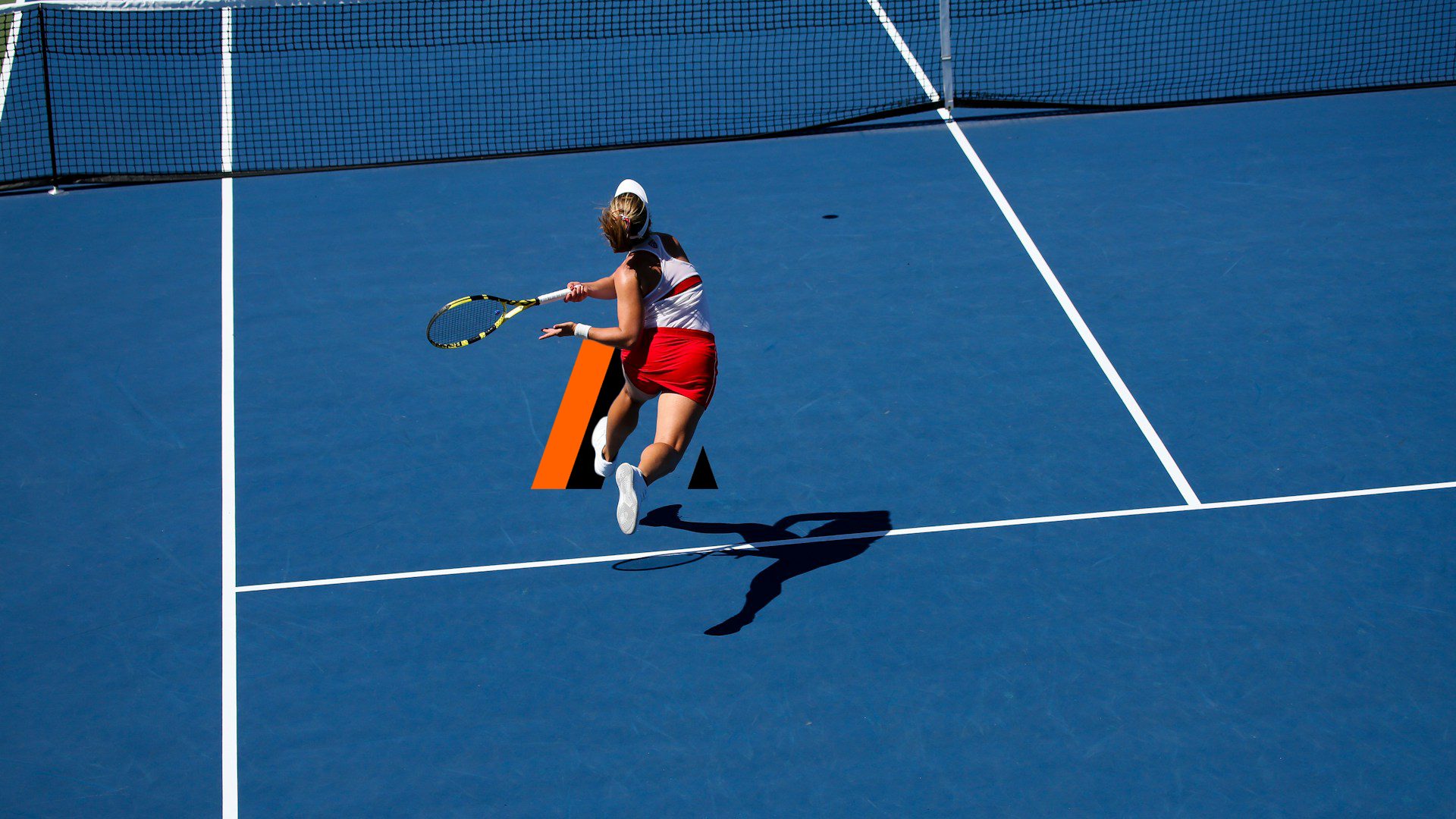 A tennis player mid-stride reaching for a forehand on an open blue court